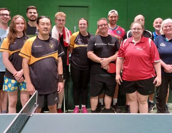 A group stand next to a Table Tennis Table looking proud