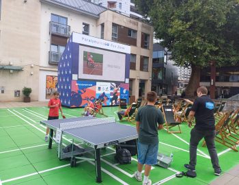 4 teenagers play table tennis in front of the big screen